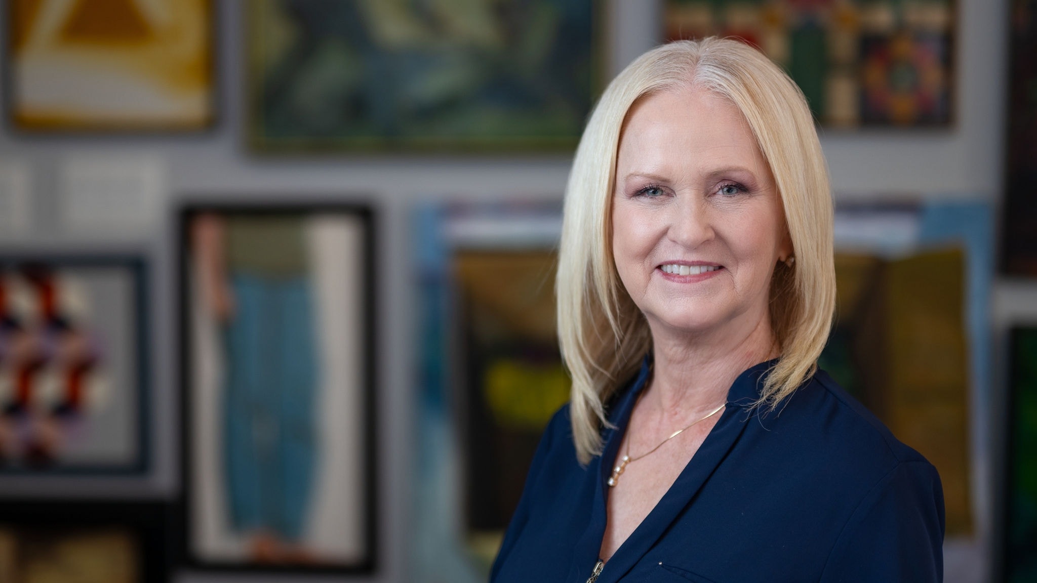 Colleen Whittoesch headshot against art wall