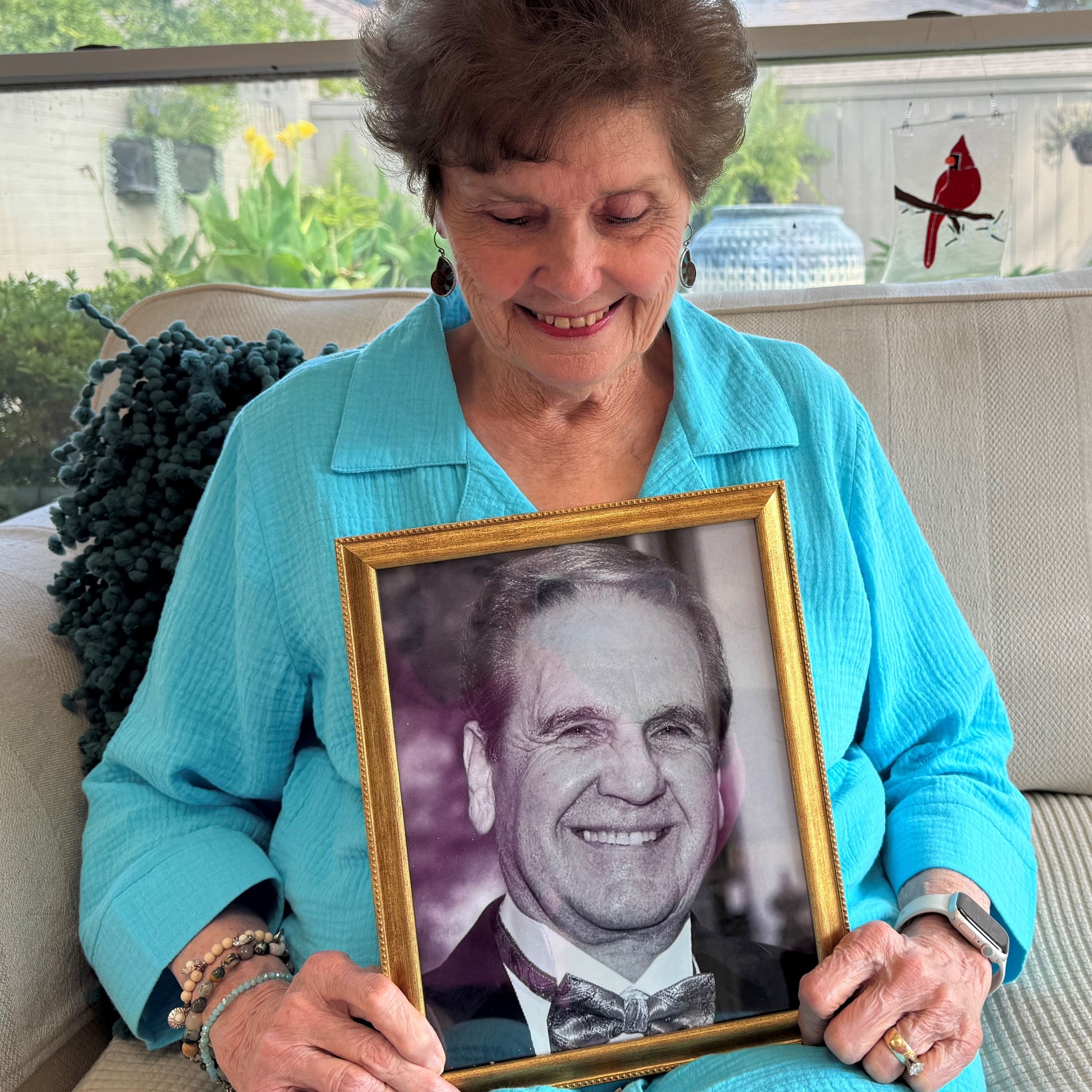 Pat Sibille smiles holding a framed photograph of her late husband, Jerry. 