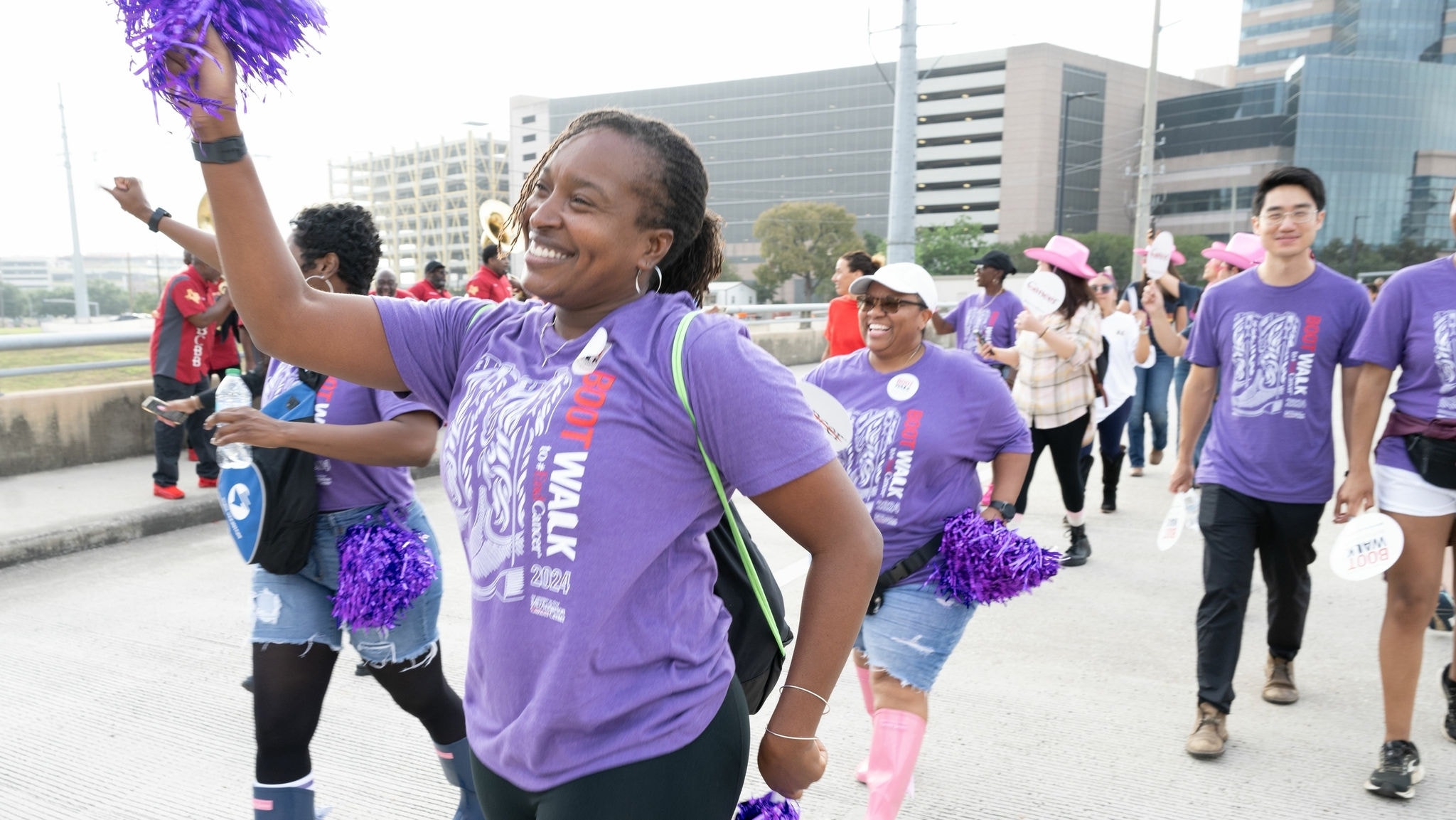 Woman in purple shirt with pom poms and others walking in 2024 Boot Walk